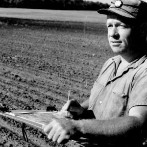 00-00-0000 Man with clipboard standing in field. Photo by Robert Mills