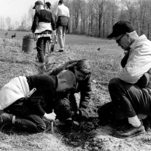 00-00-0000 Two boys planting tree seedling while leader looks on. Photo by Robert Mills