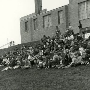 00-00-0000 Unidentified adult speaking to group of students on hill behind a building-website