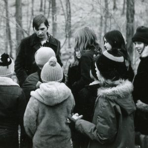 Group of stdents in winter attire gathered around man. Photo by Robert Mills