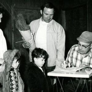 Man,woman,2 children receiving trees from older man checking them off-website