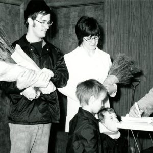 Man,woman,2 children receiving trees from young man checking them off-website