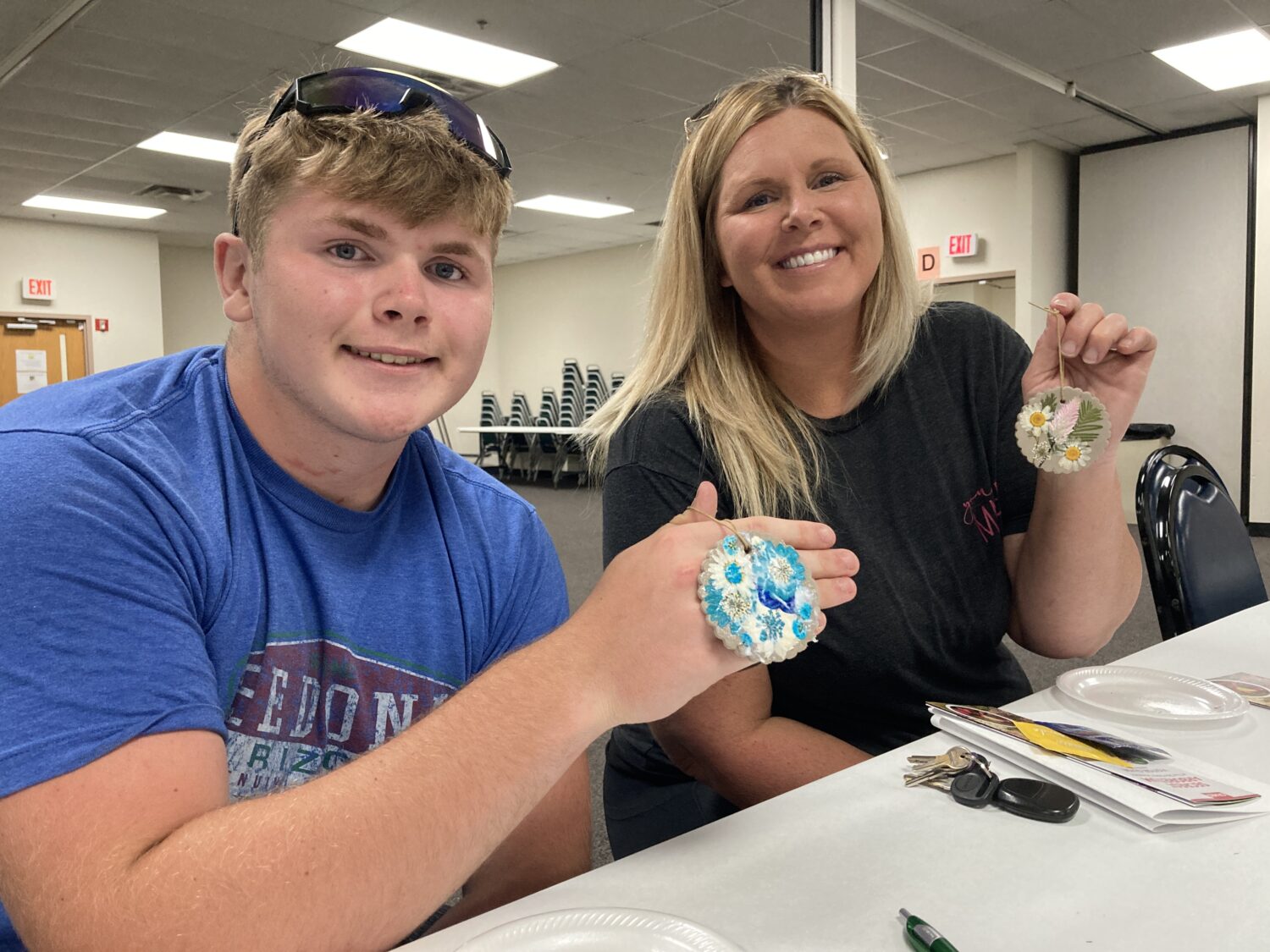Mother and son smiling at the camera holding up clay air fresheners with pressed flowers in them 