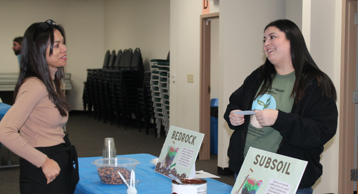 Intern speaking to a guest at the soil open house. 