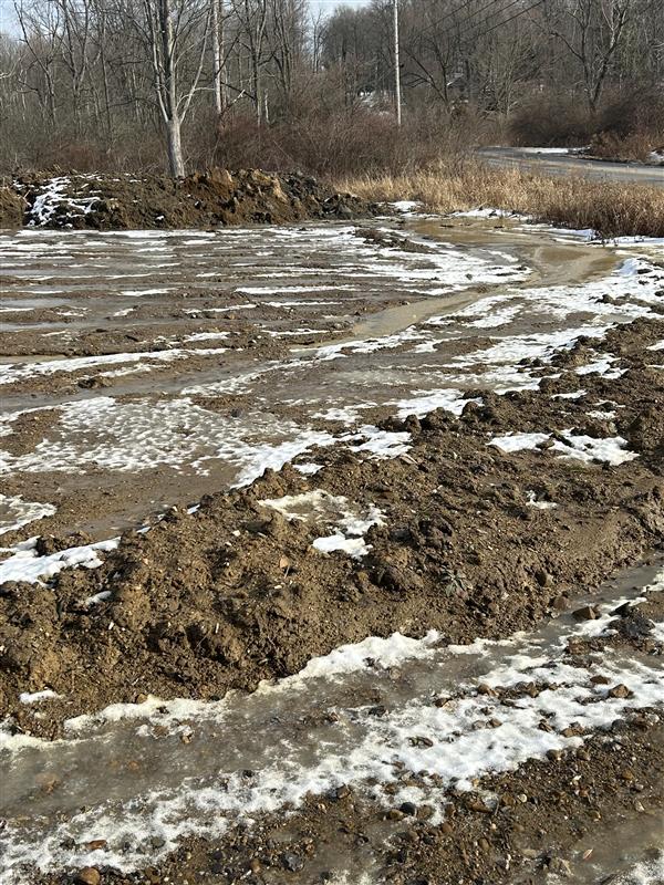 A disturbed construction site with bare soil covered in ice. 