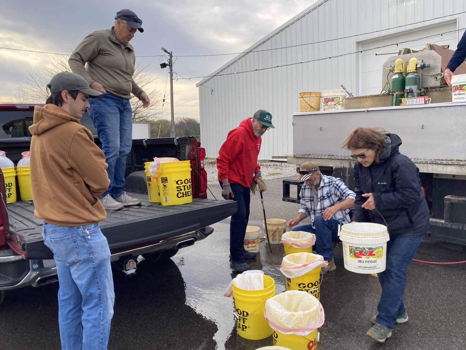 5 people gathered around buckets working the fish sale