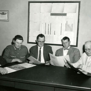 00_00_0000_Five_men_sitting_around_table_examining_documents_Website-5800