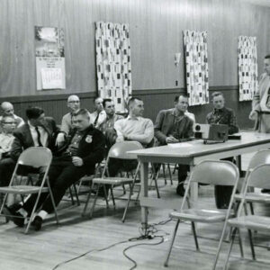 02_00_1961_Man_at_slide_projector_speaking_with_group_of_men_1_Website-5812