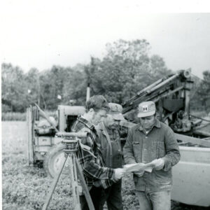 09_23_1972_Three_men_reviewing_plans._surveying_equipment_in_foreground._Machinery_in_background_website-1335