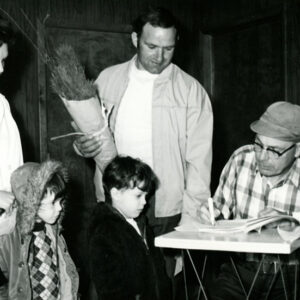 Man_woman_2_children_receiving_trees_from_older_man_checking_them_off_website-4363